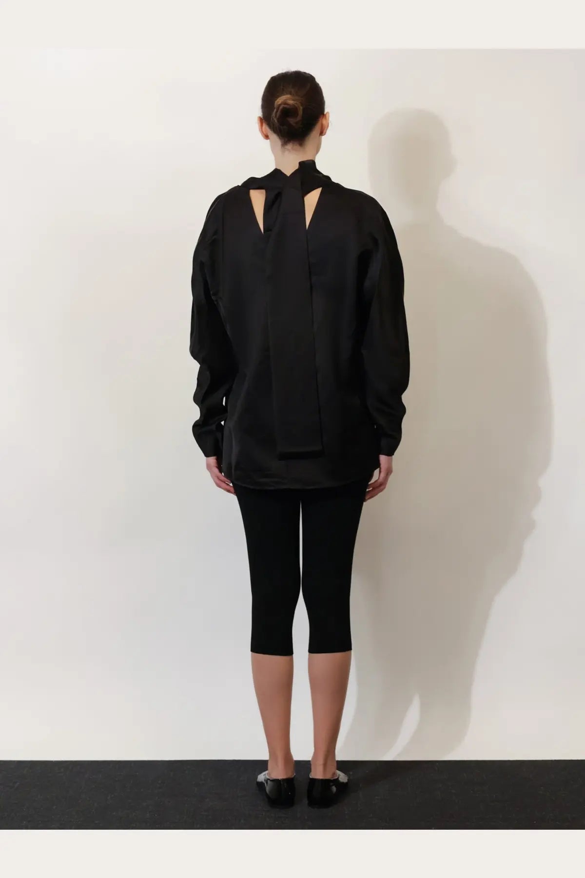 Black oversized blouse by toteme in viscose and linen with a distinctive cutout back design shown from the back side