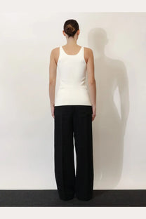 A minimalist white sleeveless top with a rounded neckline and tailored fit styled with toteme women’s black linen and lyocell blend trousers
