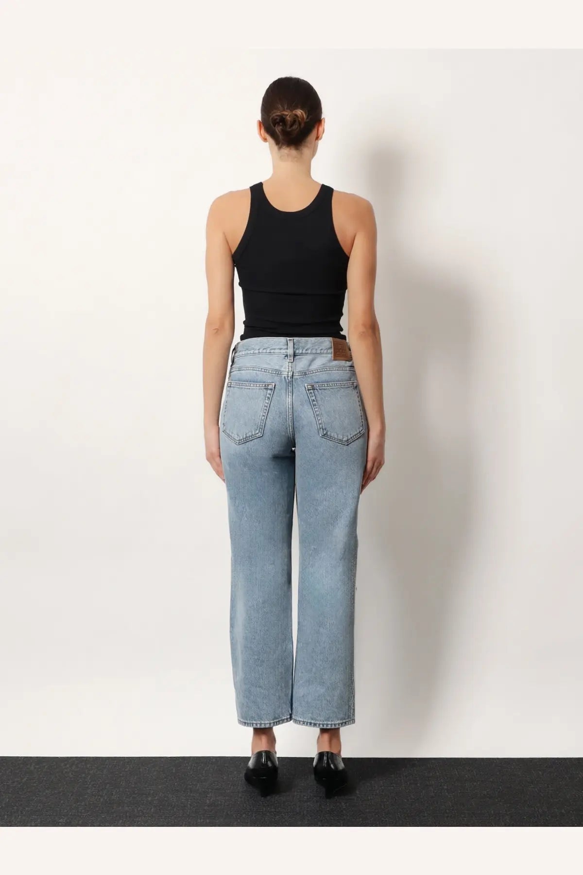 Light-wash denim jeans with high-rise wide-leg cut and classic back pockets shown from the back side