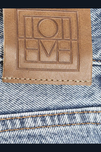 Tan leather brand patch with embossed loewe logo stitched on the back of toteme women’s low straight organic cotton grey jeans