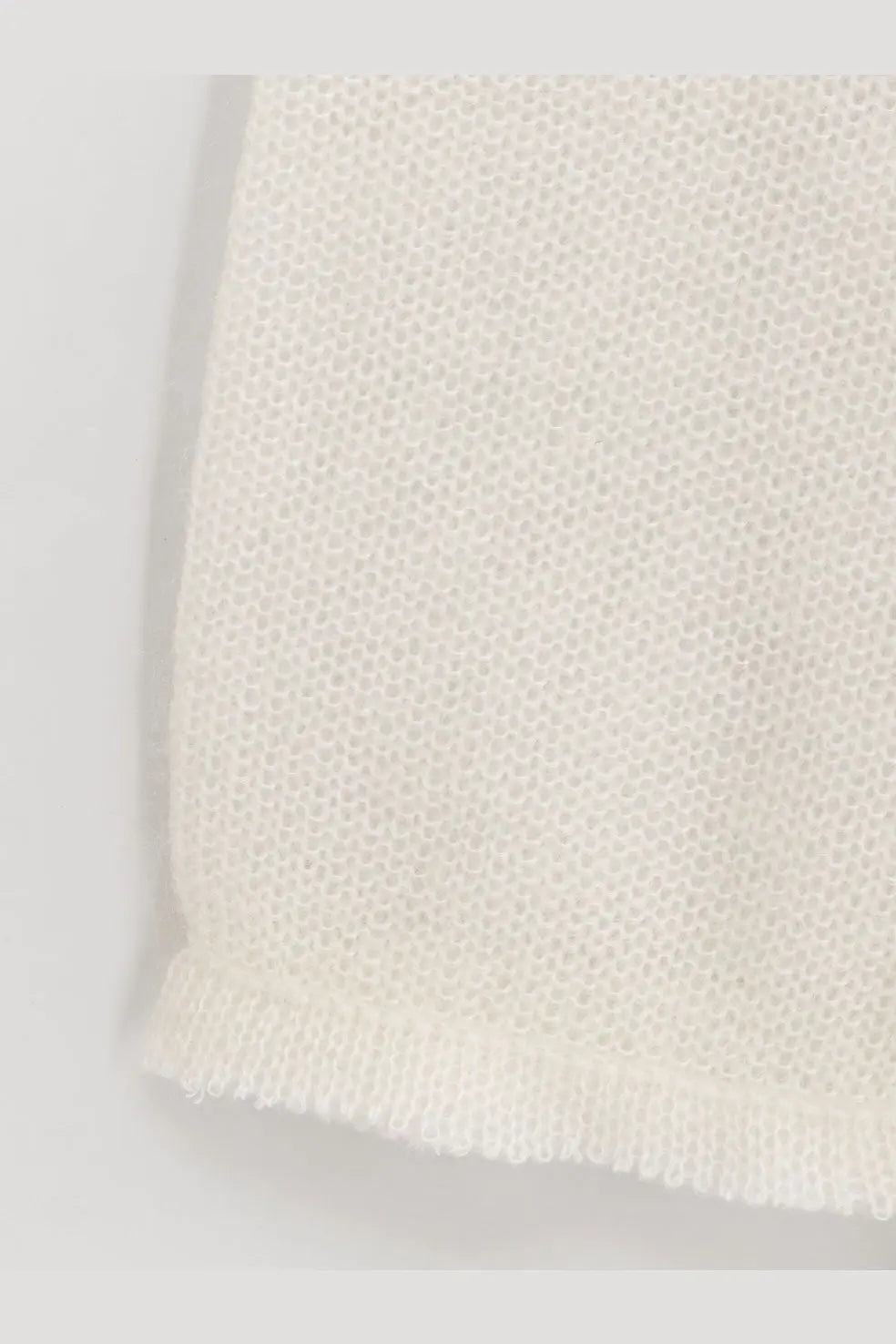 A delicate off-white knitted mohair and wool blend sweater by toteme with fine mesh pattern and softly frayed edges