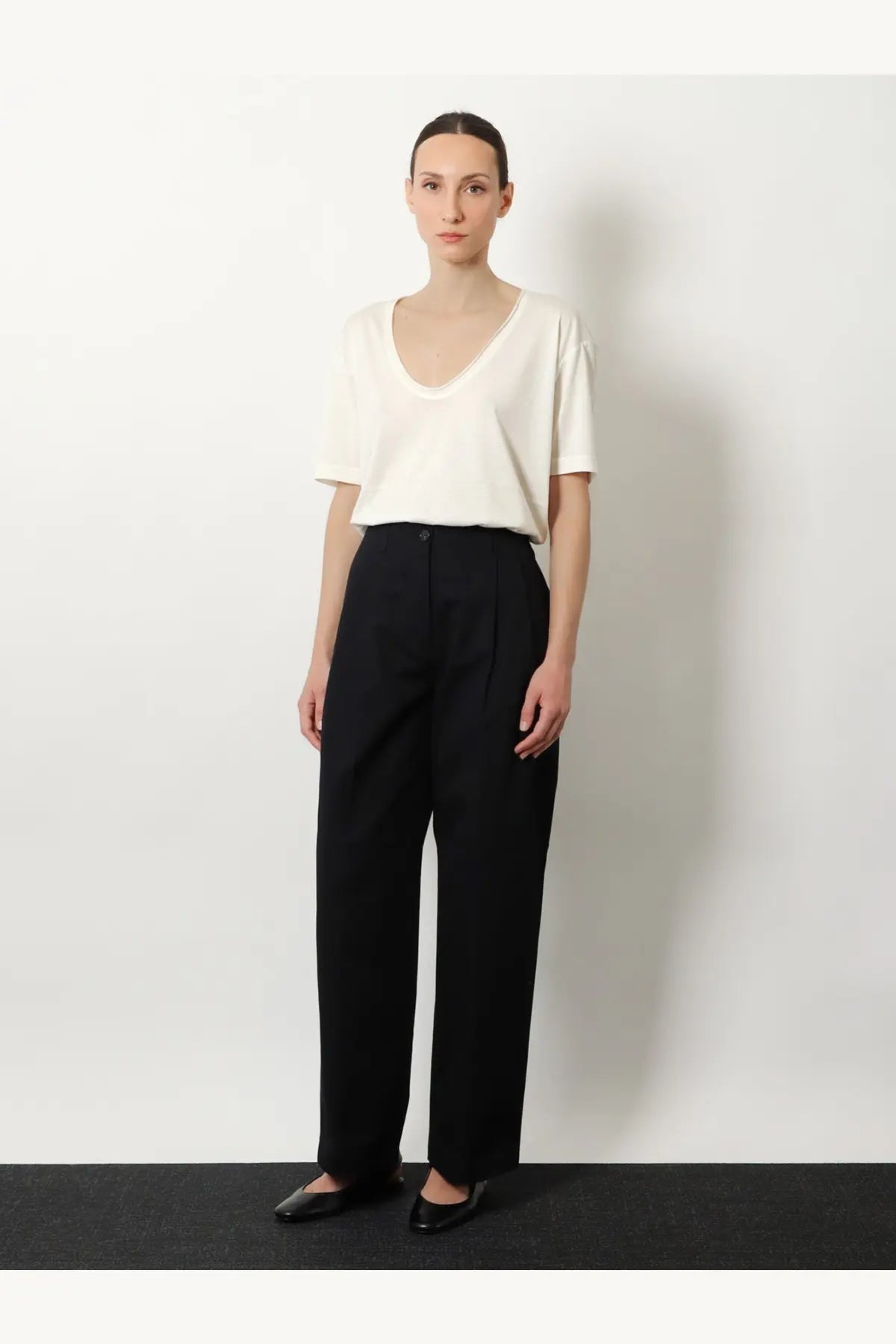Black high-waisted pleated trousers with a sleek minimalist design paired with toteme silk and cotton blend shirt white