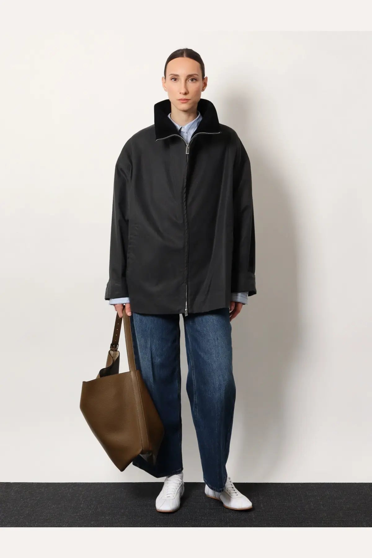 Black oversized coat with plush collar and front zipper paired with toteme women’s blue wide leg organic cotton jeans