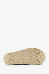 Beige rubber sole with starburst tread pattern and embossed ugg logo on ugg womens goldenstar gleam sandals suede brown