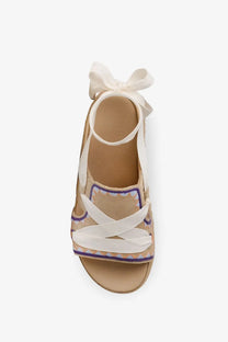 Beige UGG women’s Goldenstar hi artistitch suede espadrille sandal with white ribbon straps and decorative ankle bow