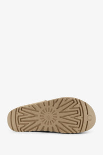 Tan rubber sole with radiating tread pattern and embossed ugg logo on ugg women’s goldenstar suede beige sandals