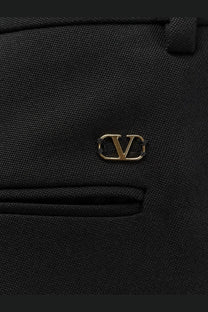 Black virgin wool trousers featuring a gold-tone Valentino logo emblem for men