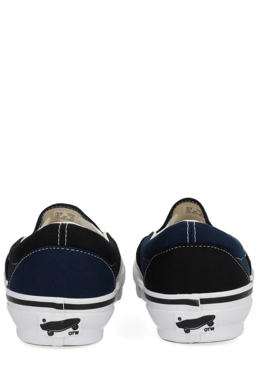 Back view of navy and black vans slip-on men’s sneakers with white rubber soles and classic skateboarding logo on heel