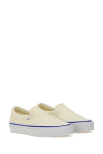 Vans unisex slip on reissue sneaker in cream canvas with white rubber sole and blue stripe featuring Vans logo on side