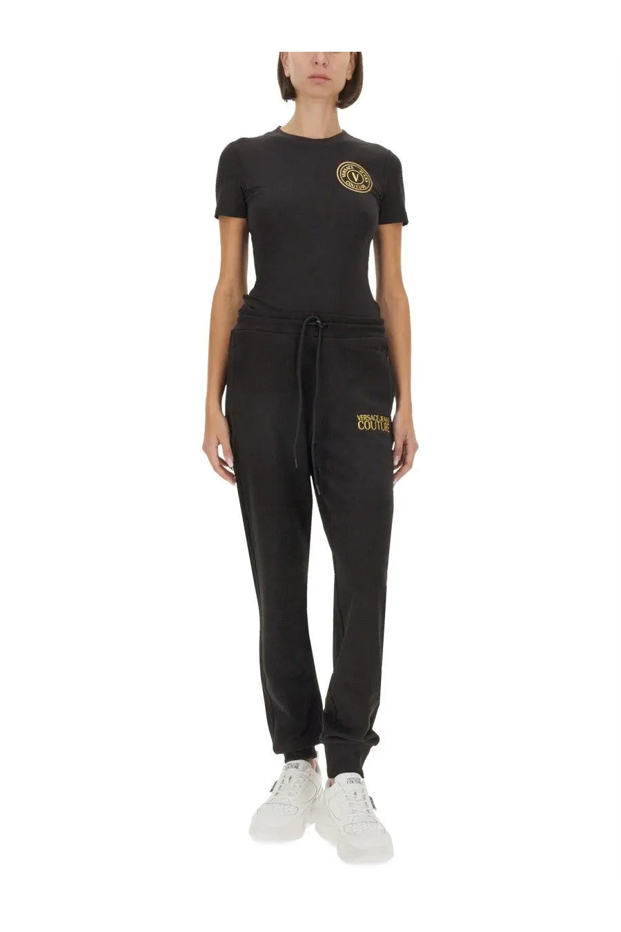 Black versace jeans couture women’s shirt paired with black sweatpants featuring gold embroidered logo on left leg