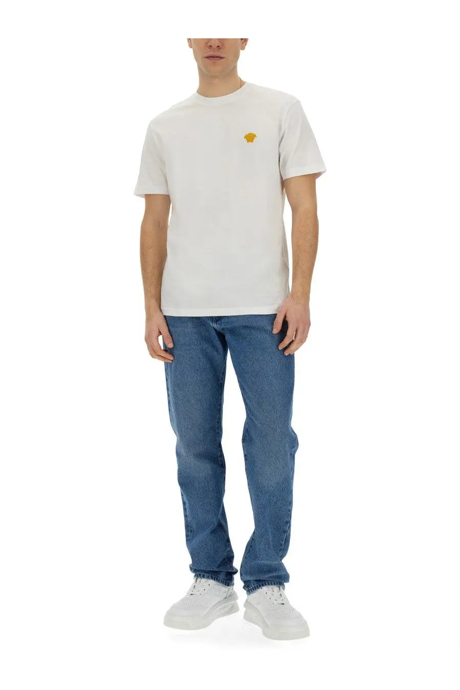 Versace men’s regular fit blue jeans paired with a white t-shirt featuring a small yellow medusa logo on the left chest