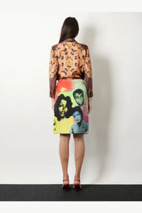 A woman wears a versace women’s printed silk twill midi skirt gold with vibrant graphic-print stylized portraits