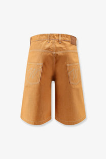 Back side of walk in paris men’s baggy orange denim shorts featuring tan cotton with white embroidered logos and leather patch