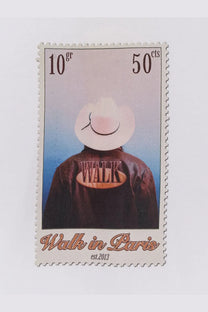 A beige and brown postage stamp featuring a person in a white cowboy hat and dark leather jacket with walk embroidered