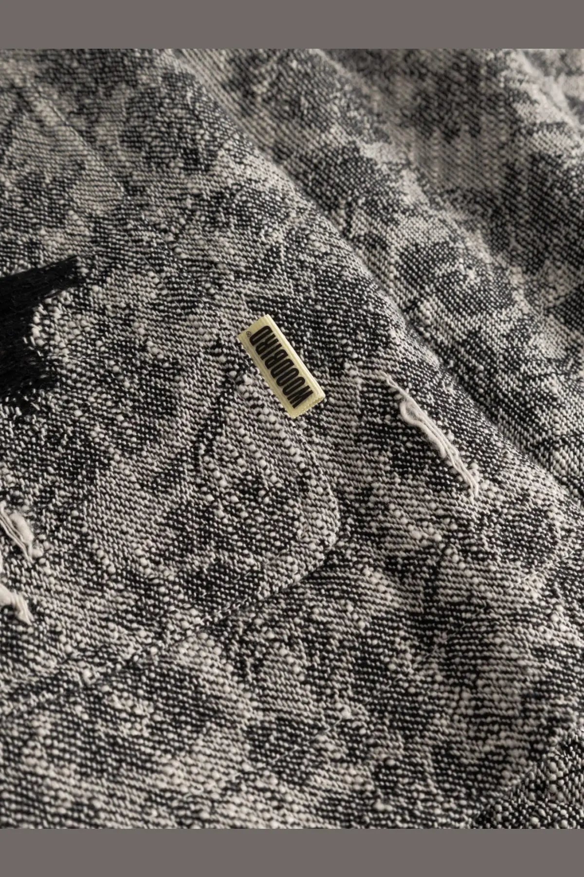 Textured black and white patterned fabric with a small label on the woodbird men’s shirt jacket black