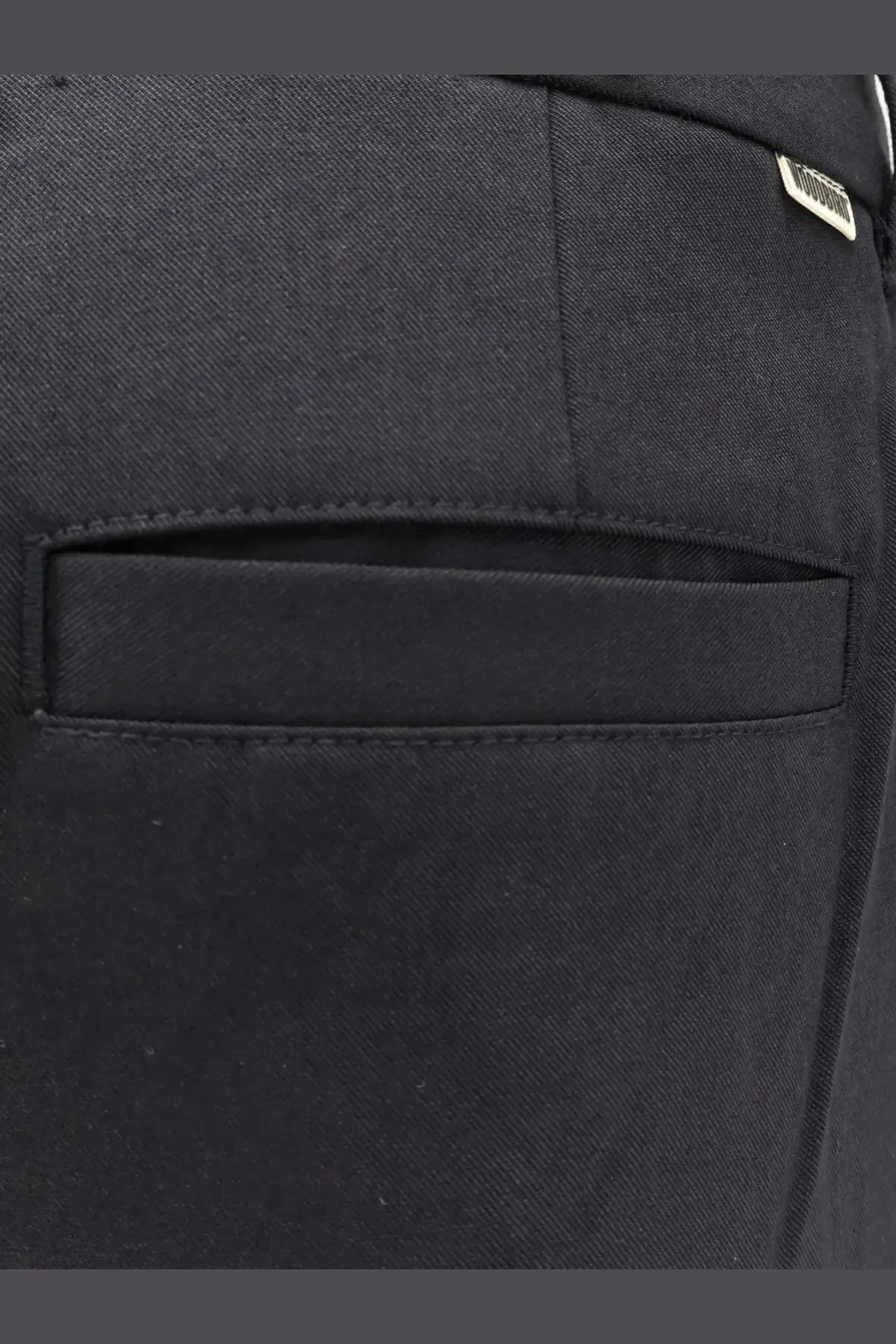 Black denim pocket with subtle woven texture and stitched edges on the back of woodbird men’s viscose blend trousers