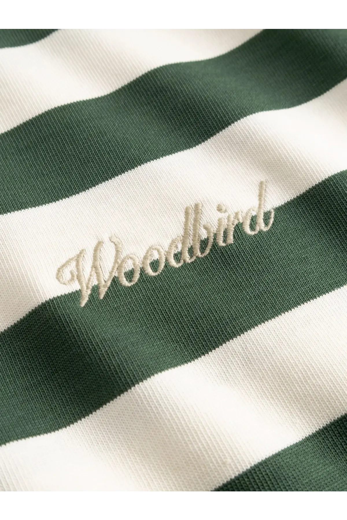 Cream-colored embroidered woodbird logo on green and white striped organic cotton woodbird men’s wbbeam tee