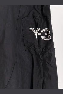 Black y-3 men’s baggy nylon cargo trousers with a distressed white logo on the side pocket