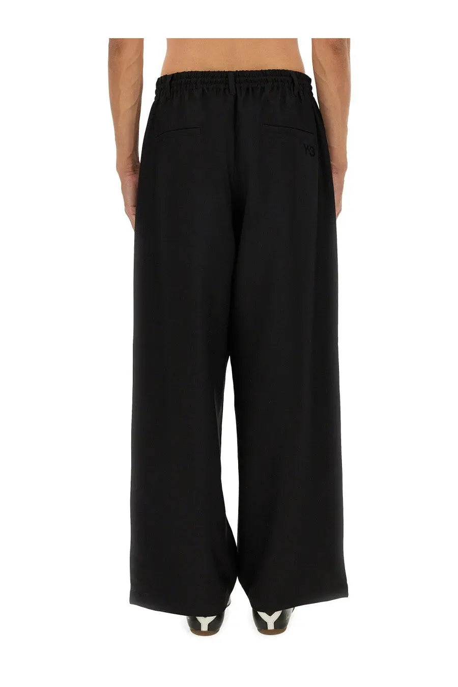 Black y-3 men’s sport uniform stripes wide-leg trousers with elastic waistband and subtle logo on back pocket shown from back