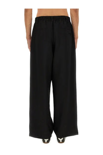 Black y-3 men’s sport uniform stripes wide-leg trousers with elastic waistband and subtle logo on back pocket shown from back