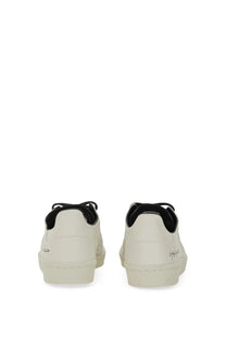 Cream-colored leather y-3 men’s superstar sneaker with black laces and subtle heel branding shown from the back