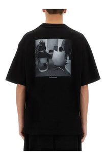Back of black ymc men’s triple jc fm oversized t-shirt with black and white photographic print of two people in chairs