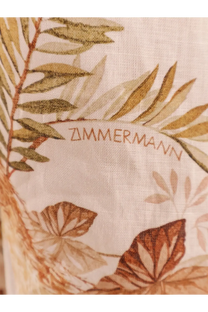 A beige zimmermann scarf with delicate olive gold and brown botanical print paired with a white linen midi dress