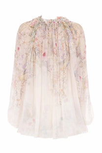 Zimmermann women’s billow rebellion blouse white is a delicate sheer blouse with pastel floral pattern and ruffled neckline